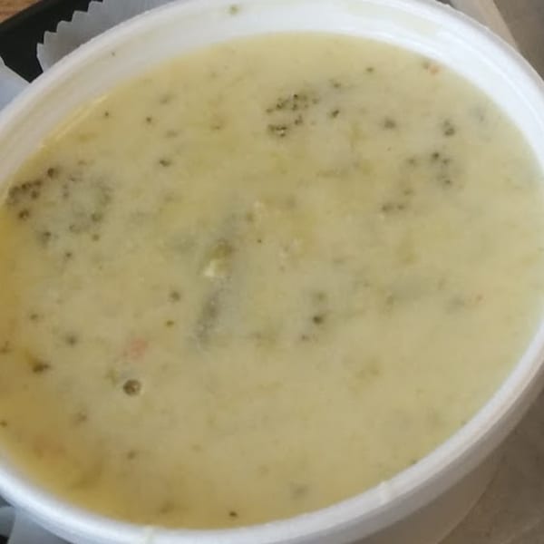 Creamy soup with visible herbs and spices in a white bowl from All American Heroes.