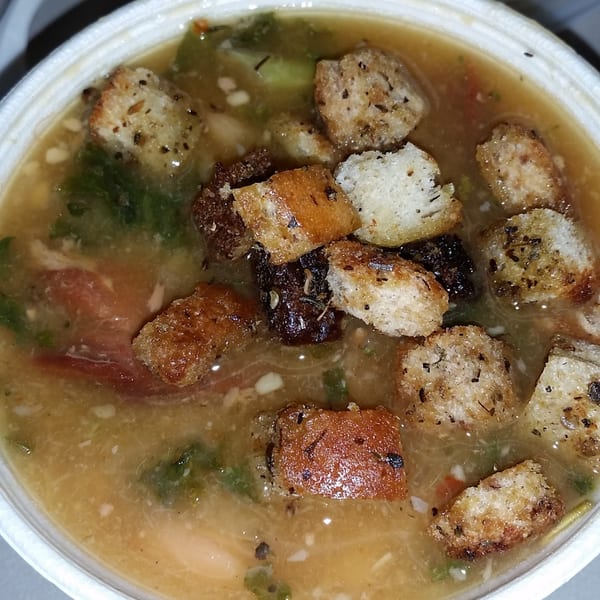 Hearty soup with croutons, vegetables, and meat in a white bowl from All American Heroes.