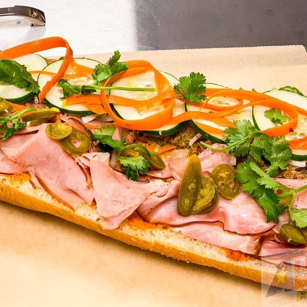 A vibrant All American Heroes sandwich with ham, pickled vegetables, cilantro, and jalapeños.